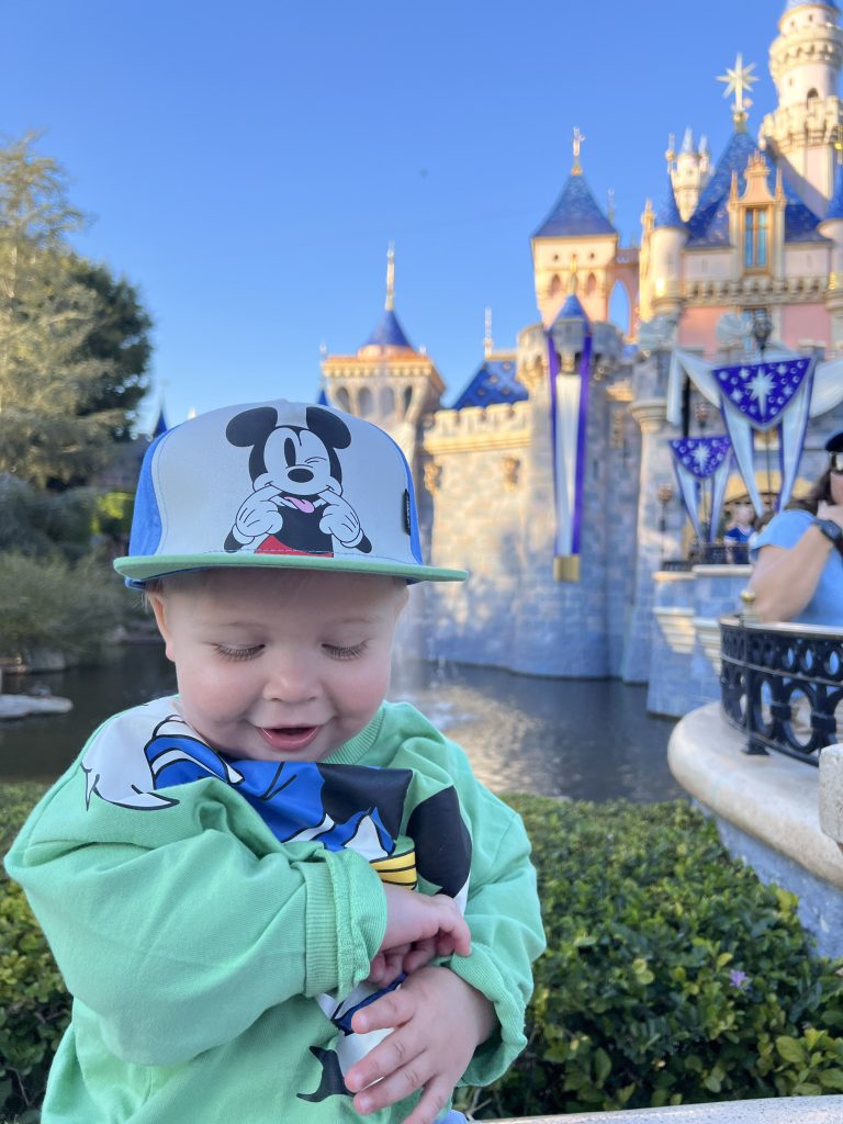 baby sitting in front of Disneyland castle